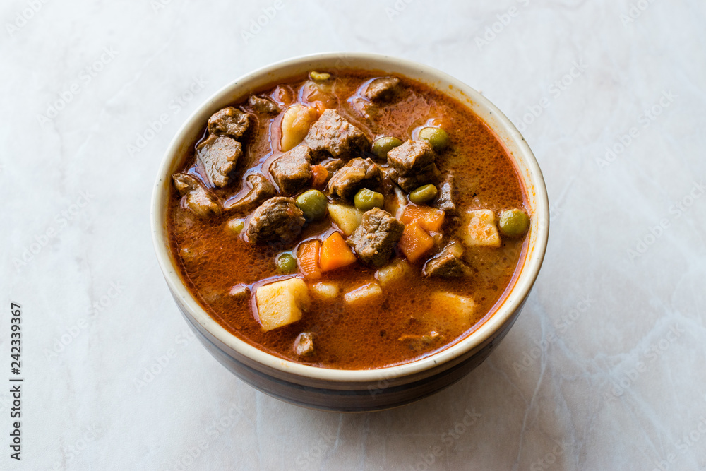 Tasty Hungarian Hot Goulash Soup Bograch or Gulas Lamb Meat Stew with Whole Grain Bread on Wooden Surface at Restaurant. Traditional Food. Tasty Hungarian Hot Goulash Soup Bograch or Gulas Lamb Meat Stew with Whole Grain Bread on Wooden Surface at Restaurant. Traditional Food.