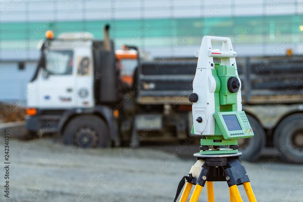 Obraz premium Surveyor equipment (theodolite) on construction site of the airport, building or road with construction machines in background