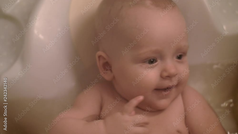 Close-up shot of lovely blue-eyed baby girl bathing. Happy little child in water Close-up shot of lovely blue-eyed baby girl bathing. Happy little child in water