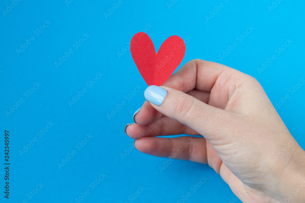 hand holding a red heart on a blue background. Background for Valentine's day.the eighth of March,place for text hand holding a red heart on a blue background. Background for Valentine's day.the eighth of March,place for text