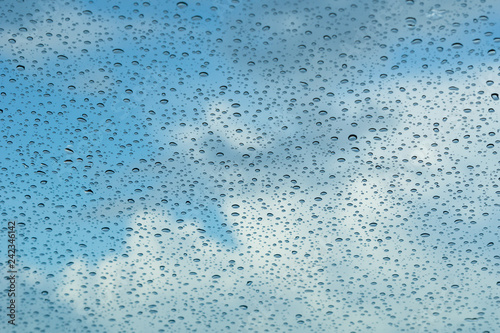 Raindrops on the windshield; in the background blue sky and white clouds, California