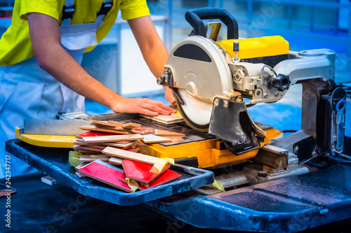 A man sawing a tile. Circular Saw. Construction works. Finishing work. A circular saw. The worker makes a cut on the circular saw.