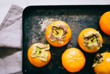 Persimmon and tangerine in black tray on a marble background