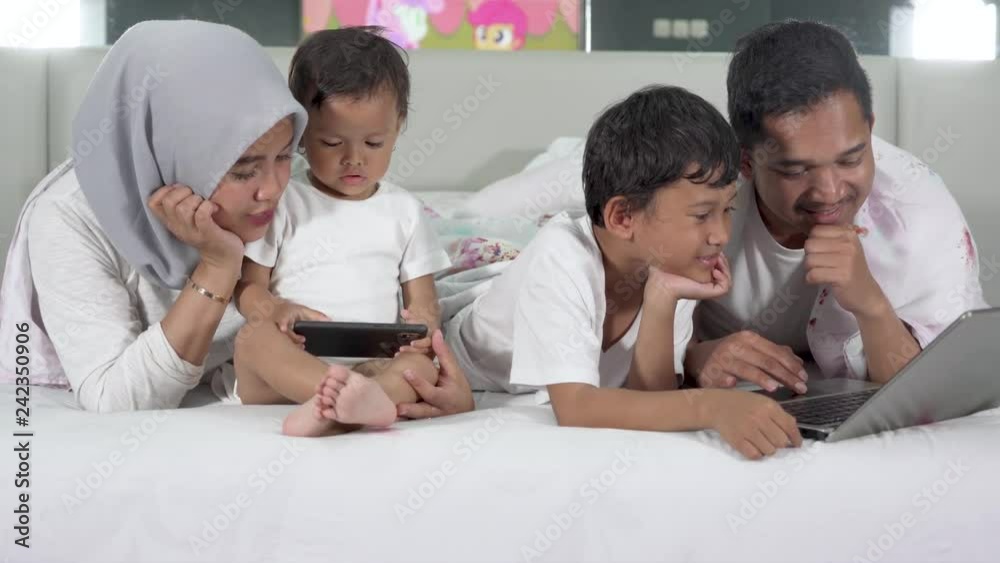 Happy young family using gadgets while lying on the bedroom. Shot in 4k resolution Happy young family using gadgets while lying on the bedroom. Shot in 4k resolution