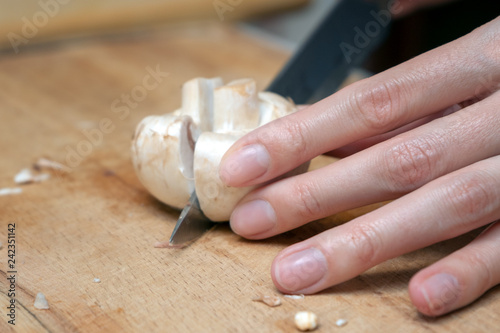 Girl cook is cutting mushrooms on a wooden Board