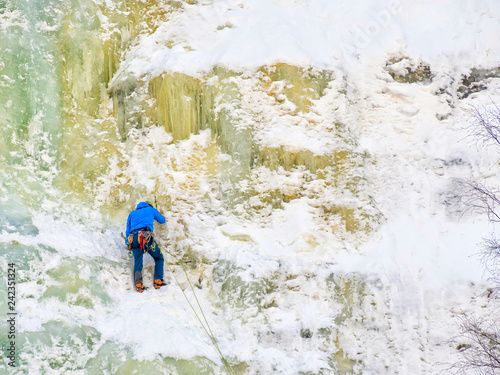 One man wearing blue jacket climbing ice wall