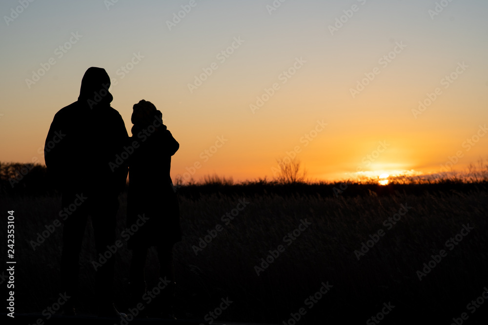 Silhouette of a couple standing and watching the sunset
