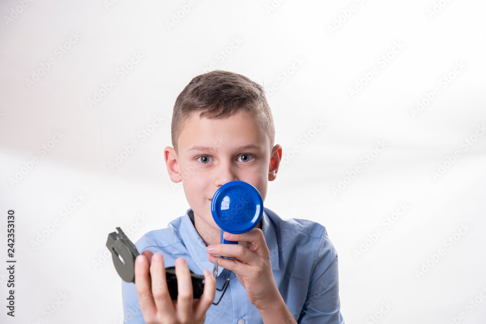 Fototapeta premium Boy explains the way with a blue megaphone and a compass in hand against a white background