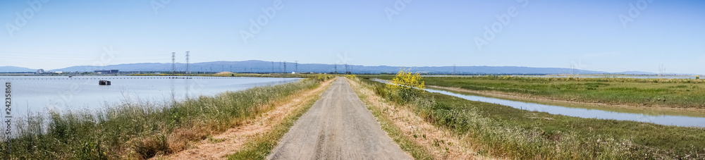 Panoramic view of levee going through the marsh and ponds in south San Francisco bay, California