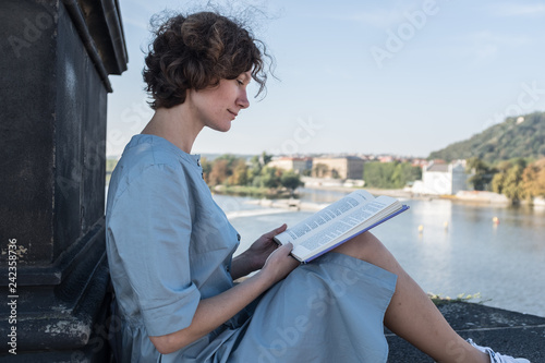 Canvas Print woman reading a book in the historical center of Prague on a sunny summer day