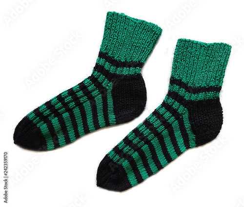 A pair of hand knitted handmade natural wool striped pattern black and green warm socks accessory isolated on the white background 