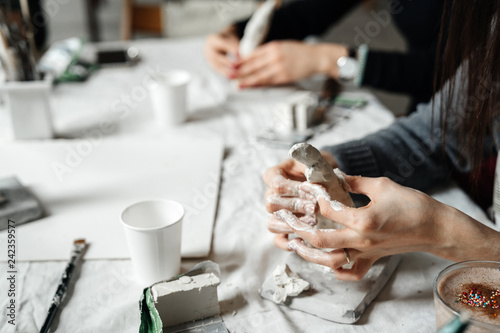 Female hands mold a decorative toy in a class for the production of clay things. Creativity and handmade.