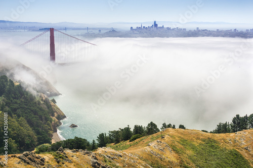 Golden Gate and the San Francisco bay covered by fog, the financial district skyline in the background, as seen from the Marin Headlands State Park, California