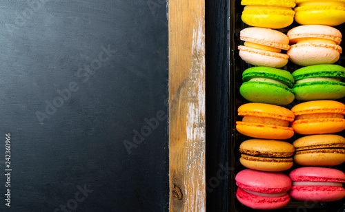 Box of colorful macarons on wooden background . Flat lay style. photo