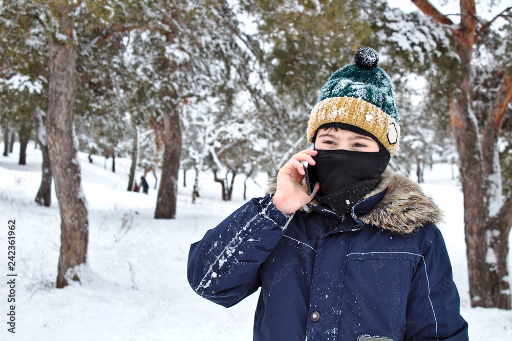 talking on the phone boy in a knitted hat with a bubo and balaclava on a winter walk talking on the phone boy in a knitted hat with a bubo and balaclava on a winter walk