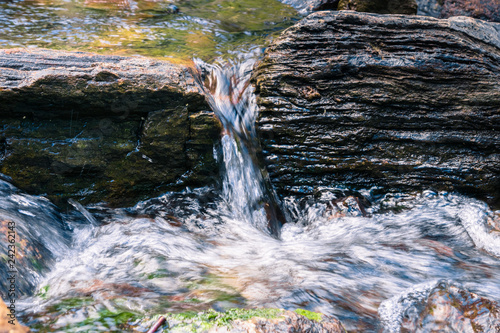 Photography Close up of water falling through rocks on the course of a creek, California