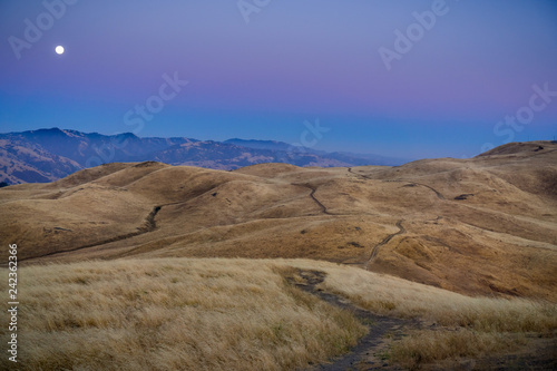Full moon rising over golden hills, as seen from Mission Peak; Mt Hamilton in the background; south San Francisco bay area, California