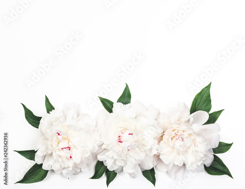 Fototapeta Naklejka Na Ścianę i Meble -  Three white peony flowers and leaves on white background. Top view with copy space. Flat lay.