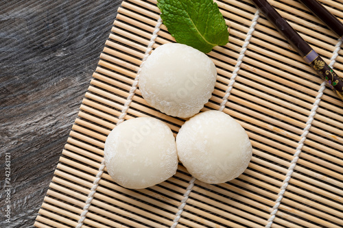 Japanese mochi with mint leaves on the wooden mat. Japan traditional rice cake.