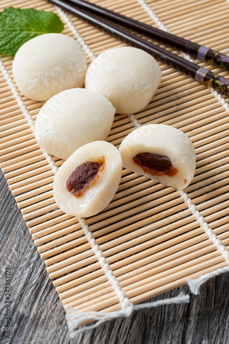 Japanese mochi with mint leaves on the wooden mat. Japan traditional rice cake.