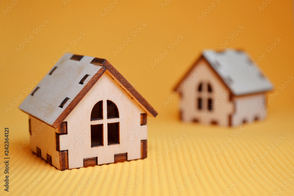 Two wooden toy house model on yellow background Two wooden toy house model on yellow background