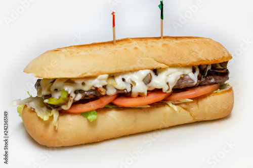 Philadelphia Cheesesteak sandwich on a sub bun with tomato and lettuce.  Tooth picks.  Isolated on white background. photo