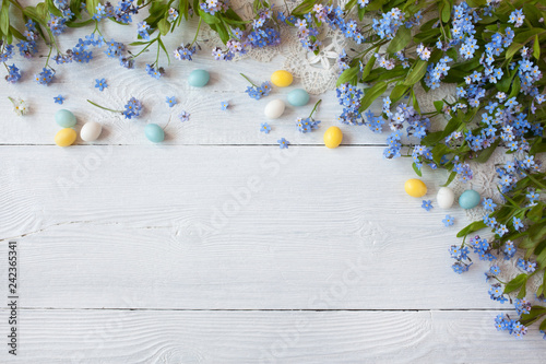 Easter wooden background with forget-me-not flowers and colored eggs