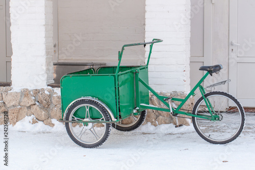 Amsterdam, The Netherlands. Winter, Green trolley on a bicycle stands on white snow.