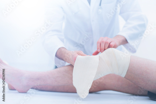 doctor bandaging patient knee
