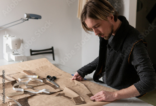 Murais de parede Male tailor creating clothing pattern while working at workplace
