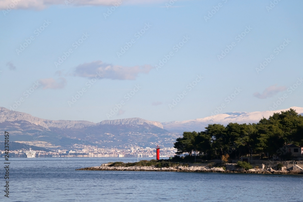 Small red solar powered lighthouse on island Solta, Croatia. View of Split in the background.