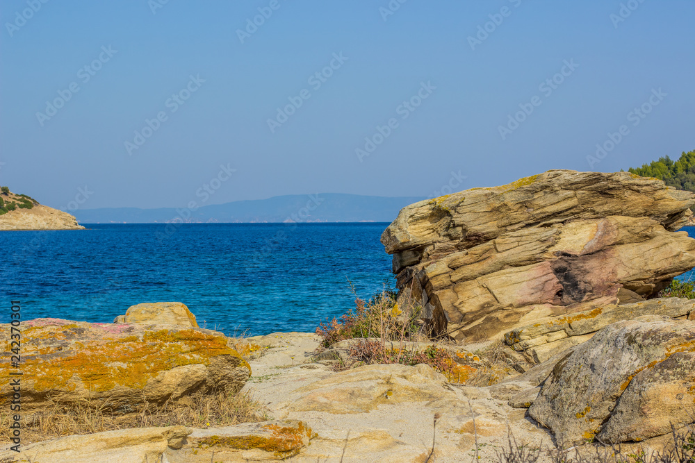 Indian ocean picturesque rocky shoreline landscape with yellow stone foreground and vivid blue water surface background, summer rest vacation holidays concept photography and empty copy space