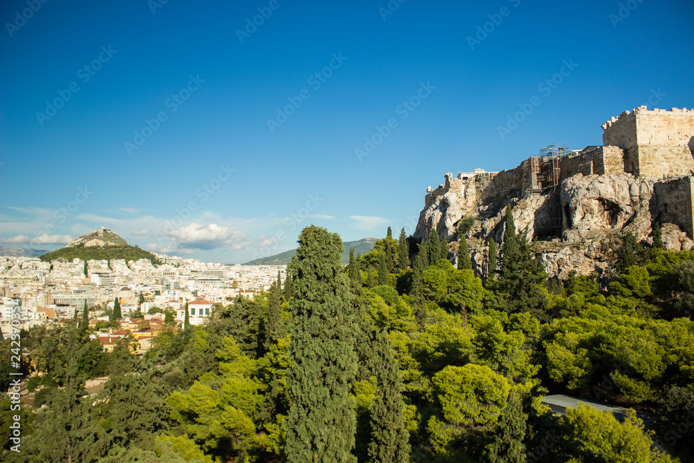 Athens - capital of Greece city country side touristic photography of rock with ancient antique ruins, many building and mountain background in shot 