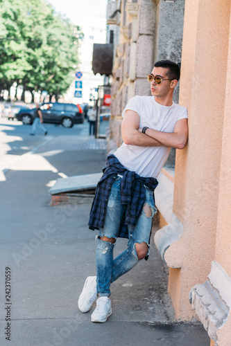 Attractive, sexy guy standing on the street in sunglasses. self-confidence, flatulence and arrogance. model, posing, portrait of a young man