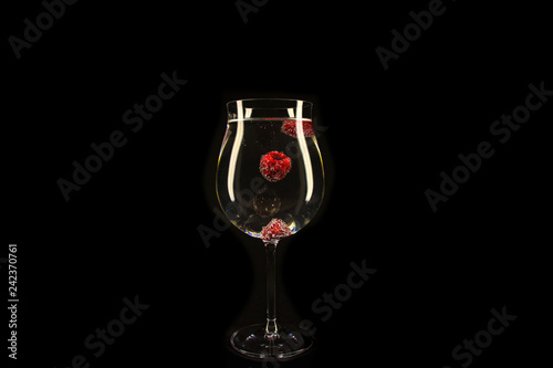 Raspberries with bubbles in a glass of carbonated drink.