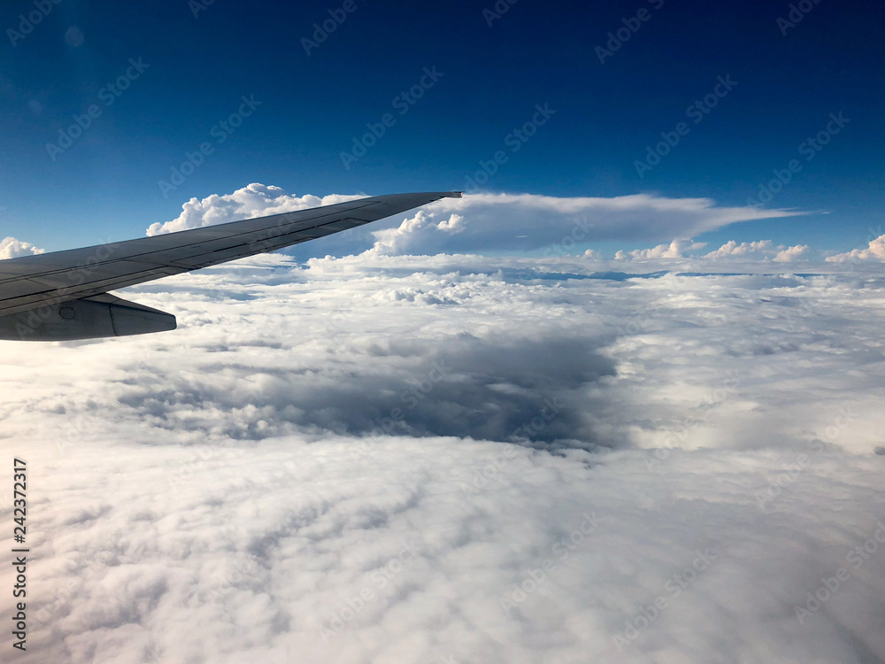 The wing of an airplane over clouds below
