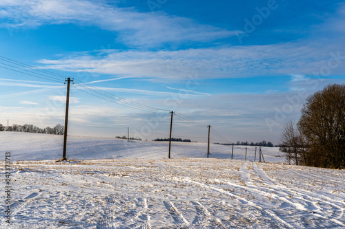 Empty Countryside Landscape in Sunny Winter Day with Snow Covering the Ground with Power Lines in Frame, Abstract Background © Reinholds