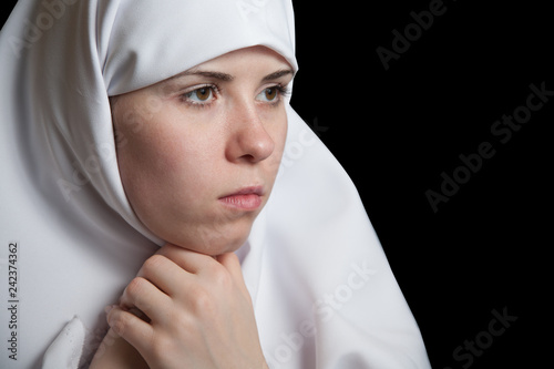 Young nun in white dress, facial closeup portrait isolated on black