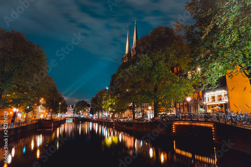 Night shot of Amsterdam canal with illuminated steeples of the church De Krijtberg in downtown Netherlands photo