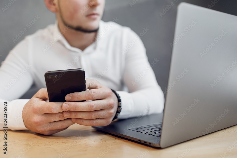 Portrait of Young man with a mobile phone sitting at cafe using laptop. Portrait of Young man with a mobile phone sitting at cafe using laptop.