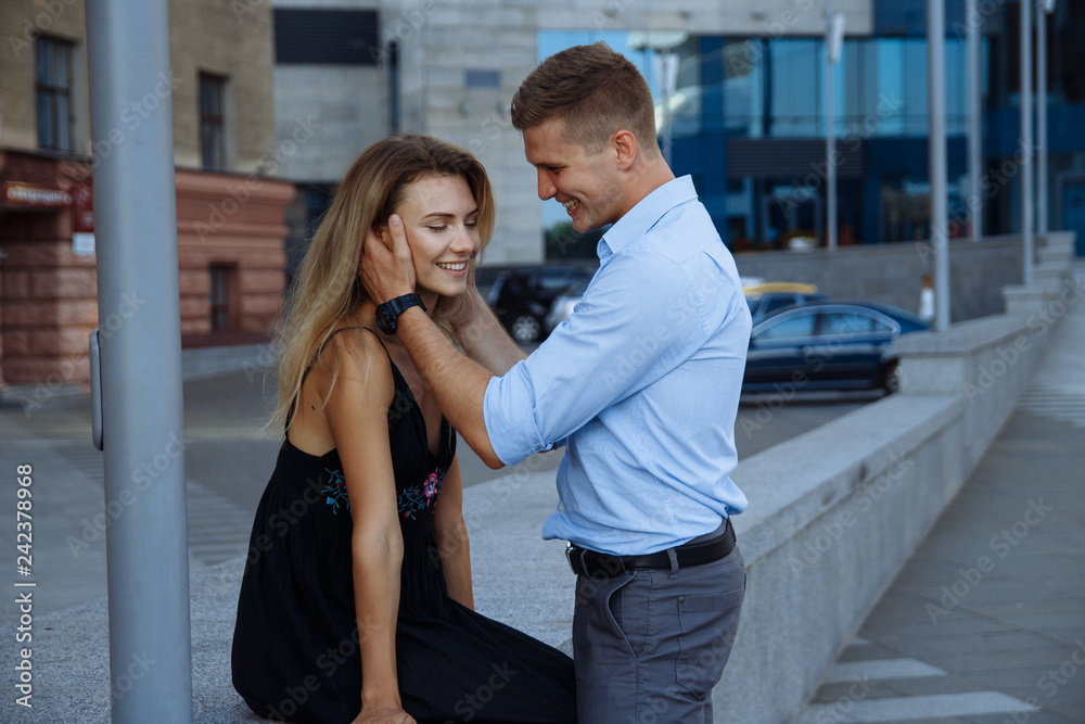 happy loving couple hugging, date in the city. black dress, blue shirt and gray pants.attraction.the man picked up the woman's head