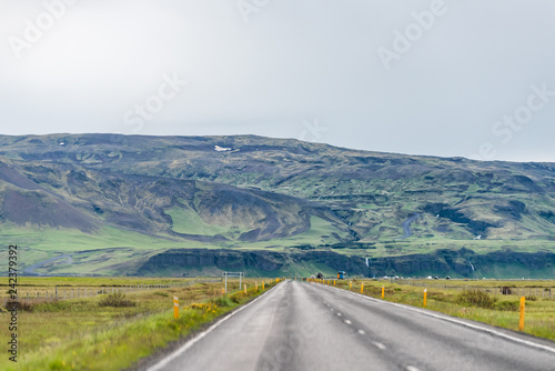 Iceland Mountains landscape view of cars on road trip by green mountain on cloudy day and southern ring road or golden circle and Seljalandsfoss waterfall in distant