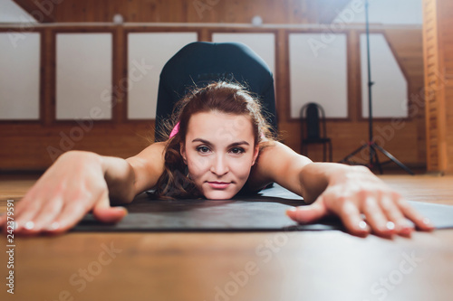 Young attractive woman practicing yoga, doing asana paired with Cow Pose on the inhale, Cat exercise, Marjaryasana pose, working out, wearing sportswear, grey pants, top, indoor full length, studio. photo