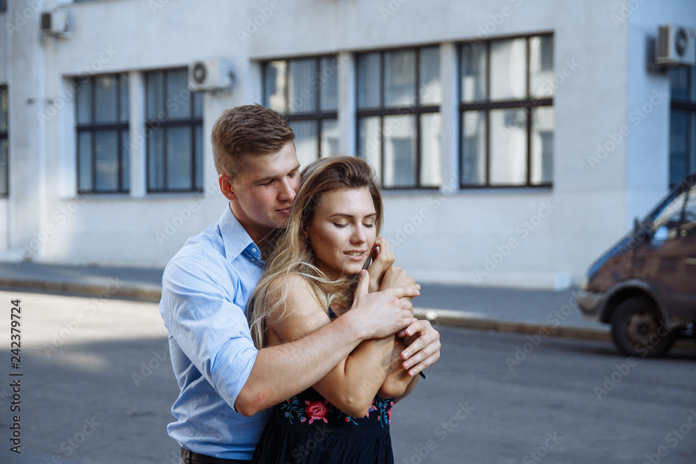 couple in love embraces against the backdrop of a building in the city, smiling, attracted. date, love Valentine's Day