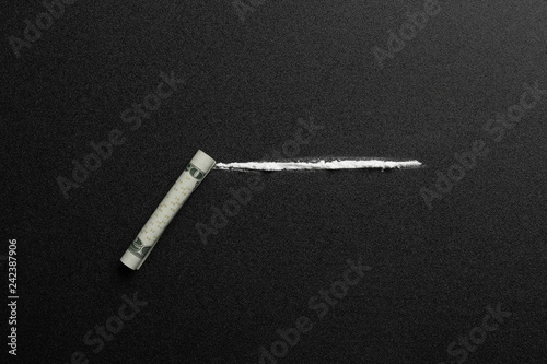 Line of cocaine and rolled money bill on dark background, top view photo