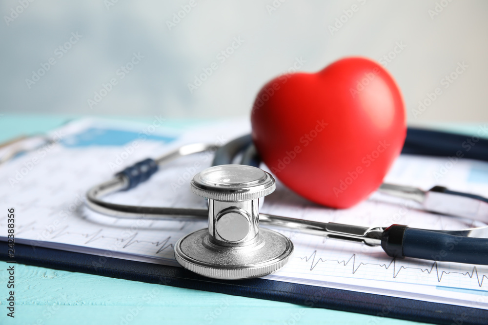 Stethoscope, red heart and cardiogram on table. Cardiology concept Stethoscope, red heart and cardiogram on table. Cardiology concept
