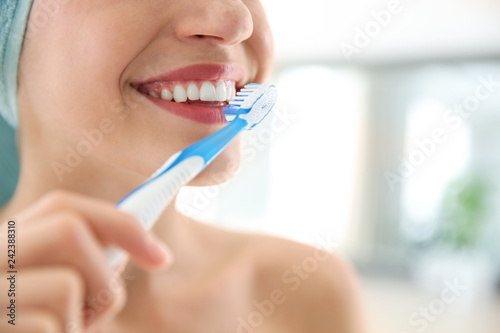 Young woman with toothbrush on blurred background  closeup. Space for text