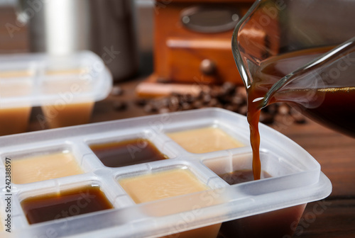 Pouring coffee in ice cube tray on table, closeup