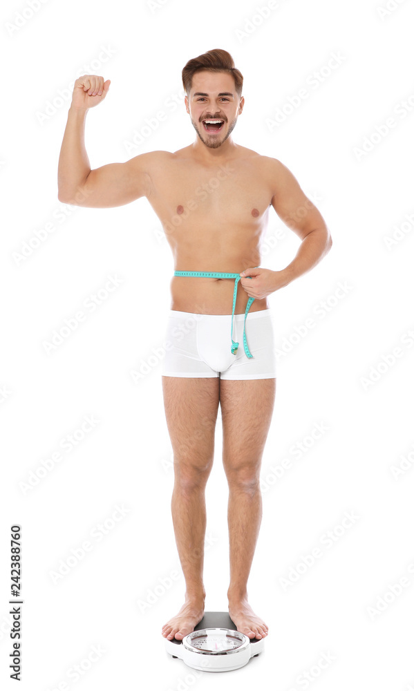 Fit man measuring his waist on bathroom scale against white background. Weight loss