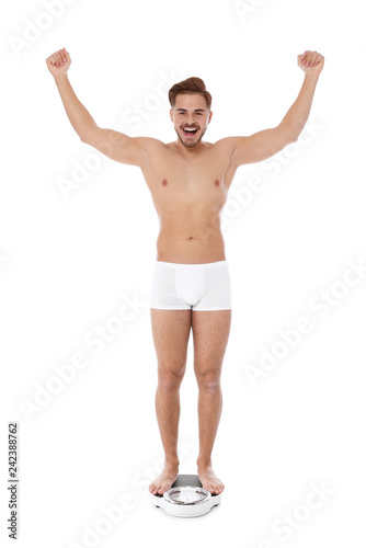 Fit man standing on bathroom scale against white background. Weight loss